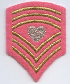 The Pink Military Chevron - Shield with Heart iron-on applique by Wholesale Applique (621022-A) features three gold chevrons and a silver glitter heart—ideal for DIY crafts or as an embroidered patch addition.