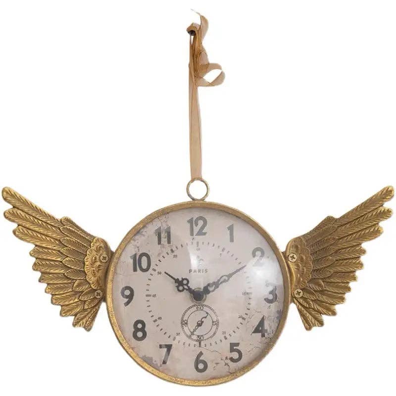 The IRON CLOCK IN GOLD FINISH by Vagabond Vintage features angel wing accents, a Paris inscription on the face, and shows 10:08, hanging by a ribbon.