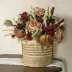 A 31" BURGUNDY SORGHUM SPRAY by Ragon House is arranged with autumn florals, pumpkins, peonies, and green leaves in a rustic basket on a wooden surface against a neutral background.