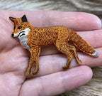 The Natural Red Fox - Walking Left - Full Body Iron on Patch by Wholesale Applique is a small, realistic patch with orange, white, and black embroidery—perfect as a red fox applique or iron on embellishment for your projects.