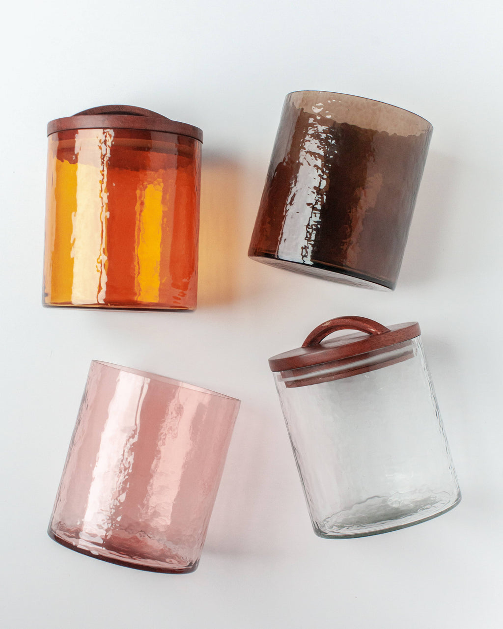 The Creative Women Handblown Hammered Glass Canisters: Smoke / Medium features handblown glass with a hammered texture and a carved wooden lid, arranged diagonally on a white background.
