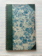 The Parcel Antique Endpaper Notebook: Large - Blue & Burgundy / Unlined features a marbled blue, white, and beige cover with a green textured spiral binding and corners, resembling vintage high-quality card stock.