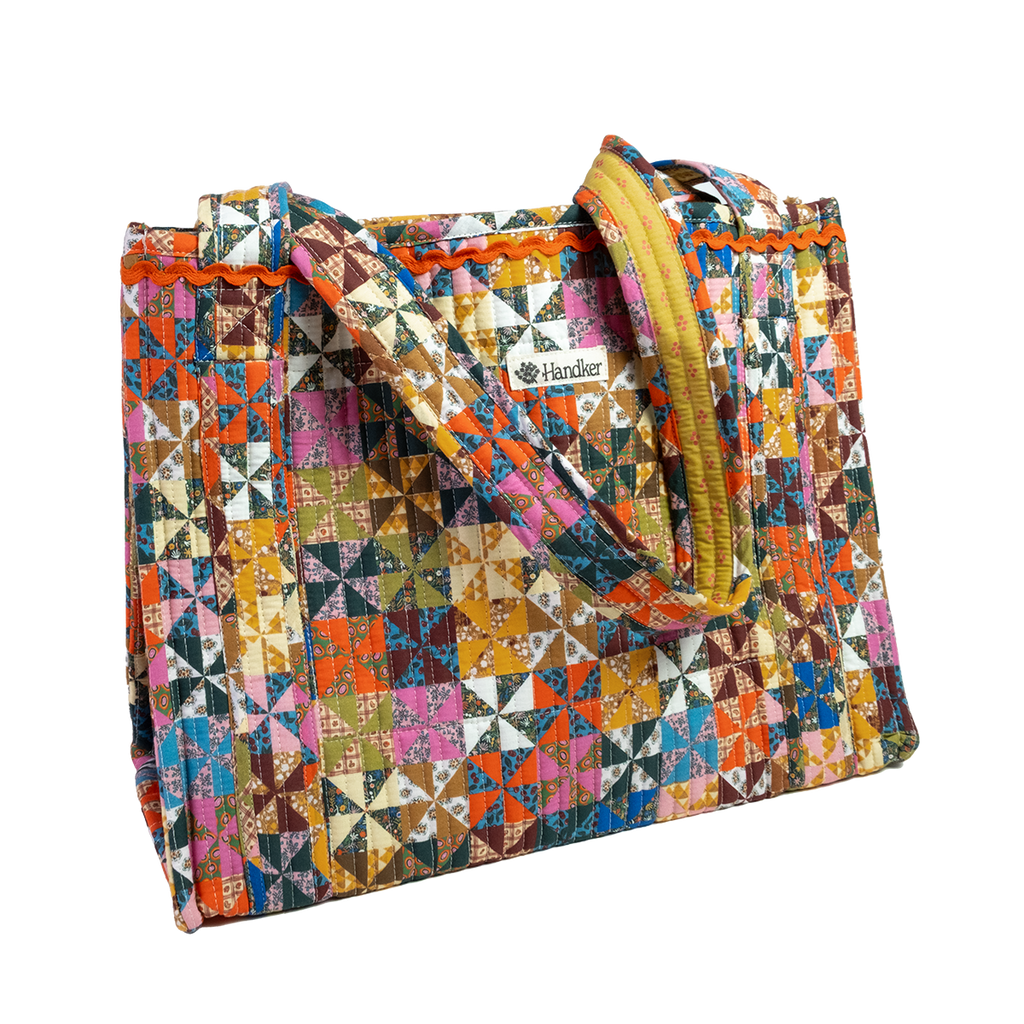 The Calico Quilted Tote by Handker Bandanas features vibrant patchwork, two sturdy handles, and a small Handker label on the front for a colorful, stylish look.