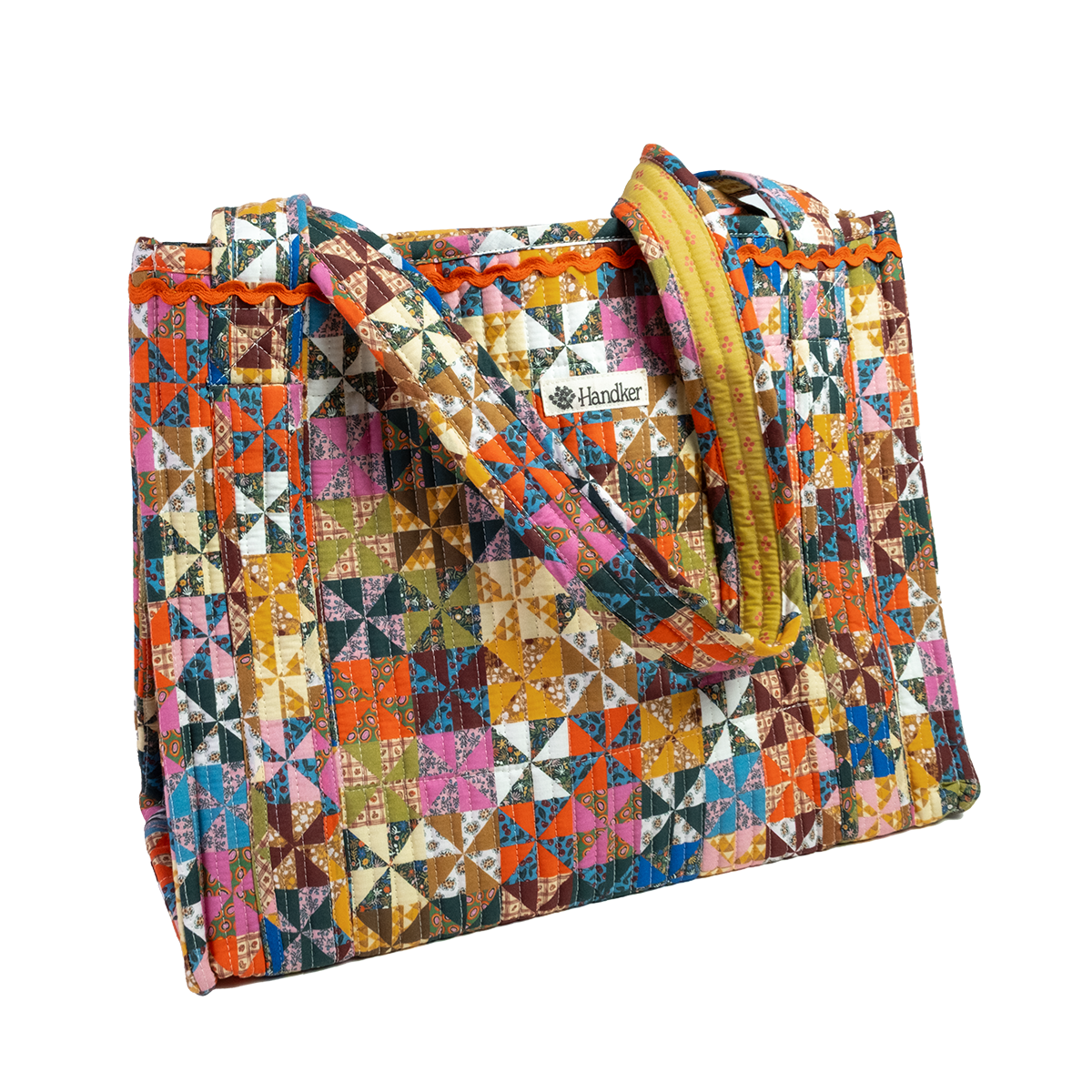 The Calico Quilted Tote by Handker Bandanas features vibrant patchwork, two sturdy handles, and a small Handker label on the front for a colorful, stylish look.