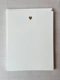 A square white Parcel card ("Tiny Heart: Silver") with a small silver foil heart near the top sits atop another white card on a light grid-patterned surface.
