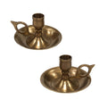 The Madison Bay Co. Brighton Bun Traveling Chamberstick Set features two vintage-style brass chambersticks with round drip trays and looped handles, inspired by antique originals, displayed on a white background.