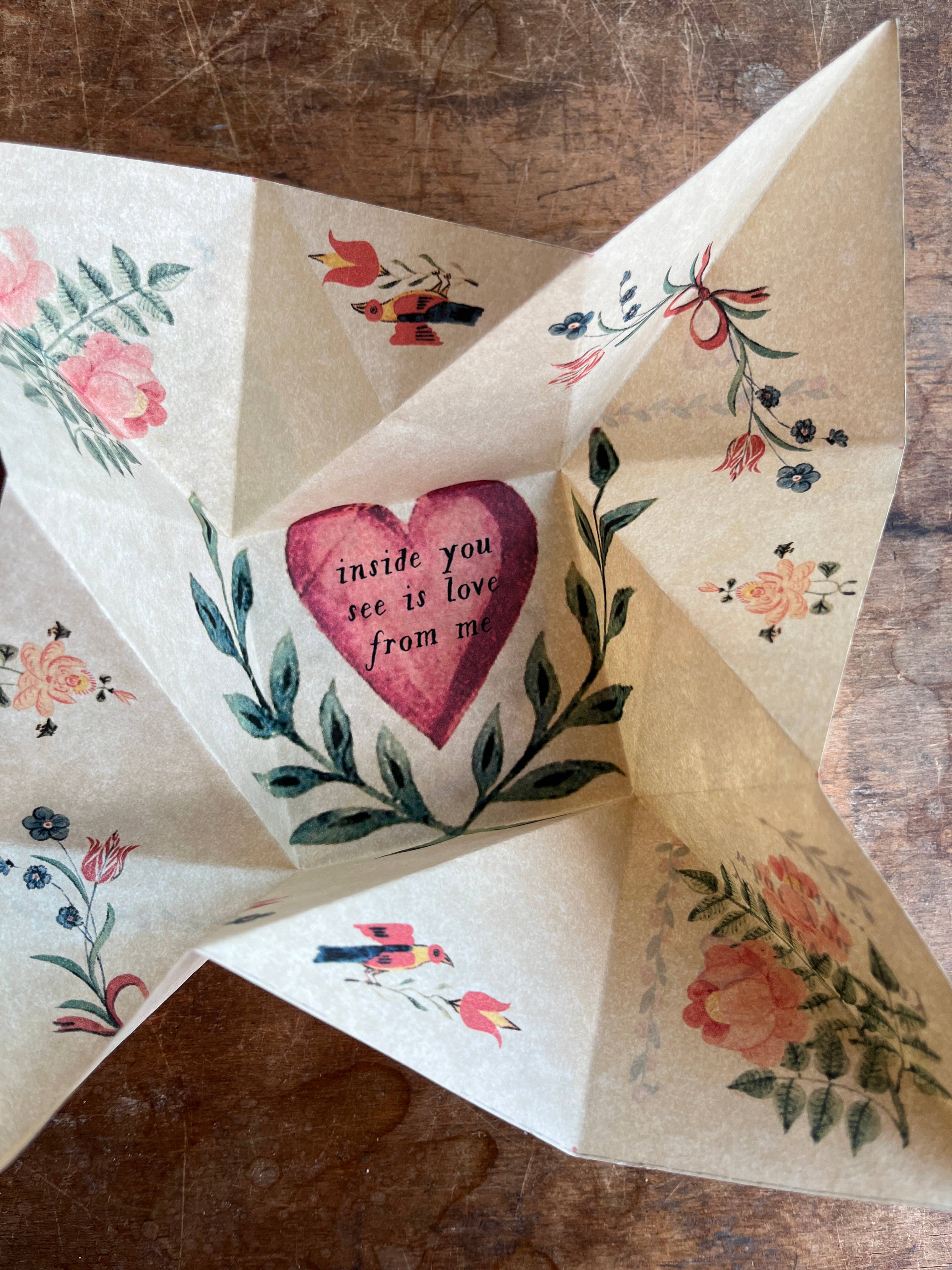 On a wooden surface, the Victorian Valentine Puzzle: Romantic by Parcel unfolds to reveal floral art and a central pink heart with the handwritten message: inside you see is love from me.