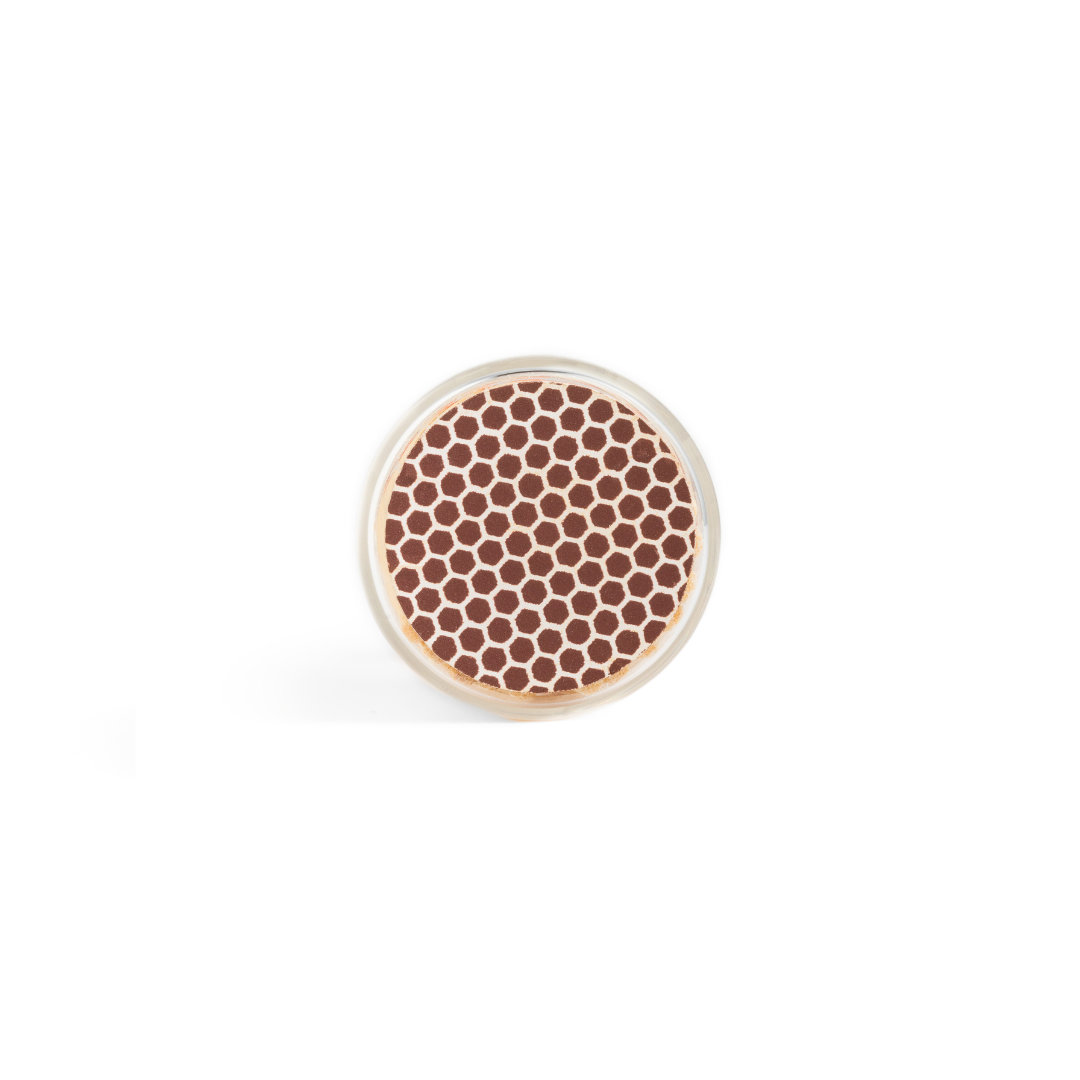 A vial of Black Matches by Enlighten the Occasion, seen from above, shows a round arrangement of small brown and white hexagonal tips resembling a honeycomb against a plain white background.