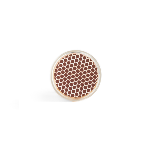A vial of Black Matches by Enlighten the Occasion, seen from above, shows a round arrangement of small brown and white hexagonal tips resembling a honeycomb against a plain white background.