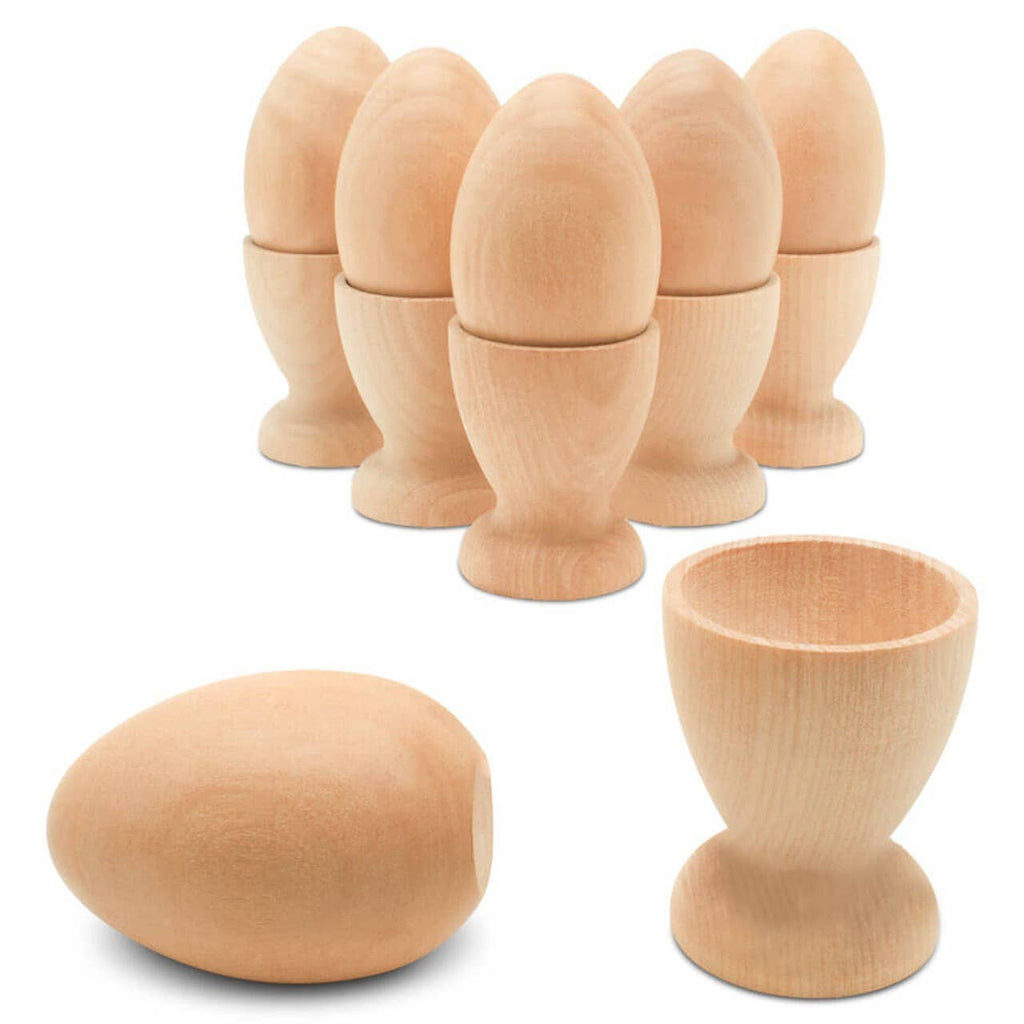 A set of seven smooth, unfinished Wooden Egg Cup Holders by Woodpeckers Crafts is displayed, each paired with an egg. One egg and one flat-bottom holder are placed separately in the foreground.