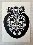 Papercut Heart Art Cards by Parcel feature black paper-cut designs of mirrored horses, birds, and foliage in a heart shape on white paper. Each 5x7 card comes with a creamy white envelope and is displayed on graph paper.