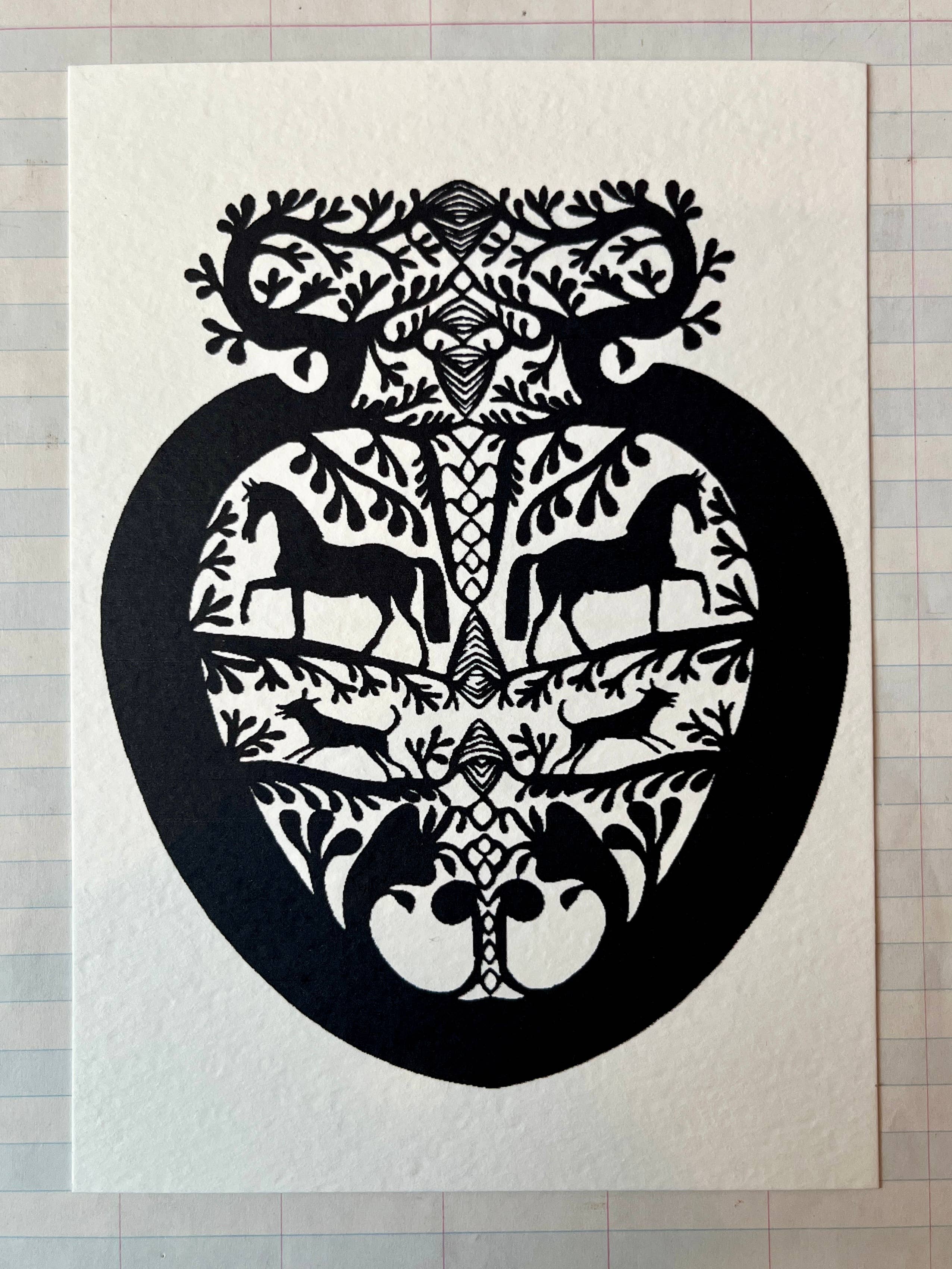 Papercut Heart Art Cards by Parcel feature black paper-cut designs of mirrored horses, birds, and foliage in a heart shape on white paper. Each 5x7 card comes with a creamy white envelope and is displayed on graph paper.