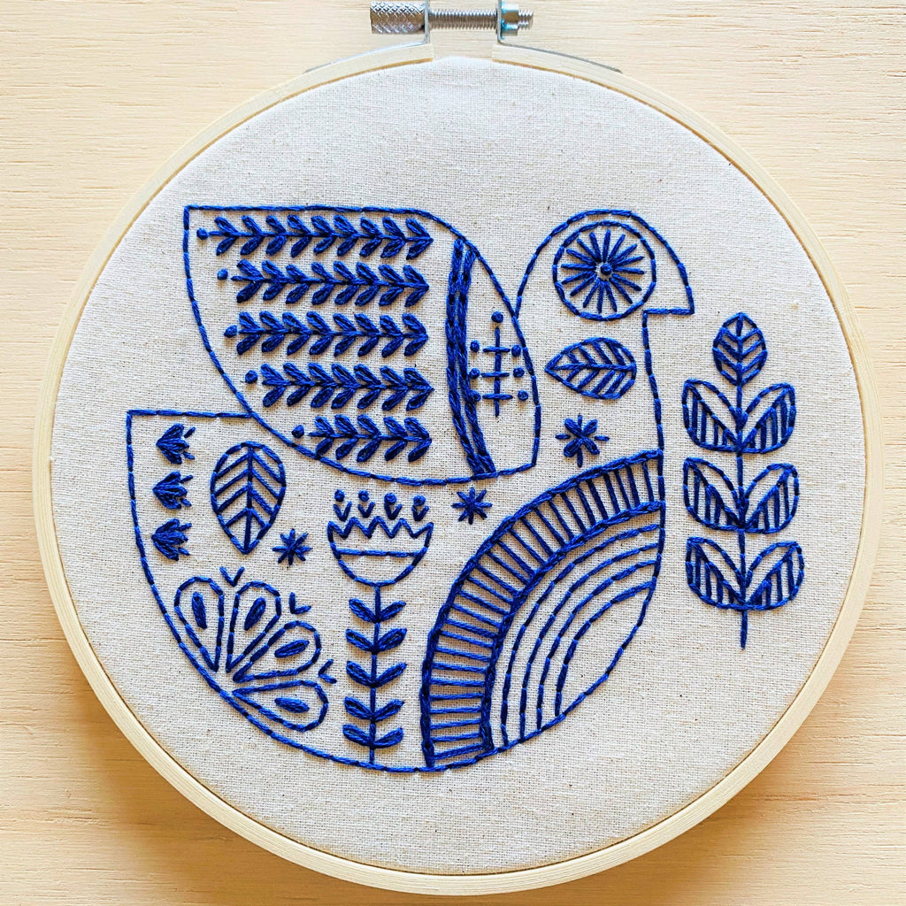 The Hygge Dove Complete Embroidery Kit by Hook, Line & Tinker features a charming blue and white bird—ideal for crafters of any level.