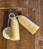 Two British-style Beeswax Stubby Candles by Yarrow Bone Farmstead, hand-dipped and full of rustic charm, rest on a wooden table. One features a label reading: Hand-Dipped Beeswax Candle—authentic from Minnesota.