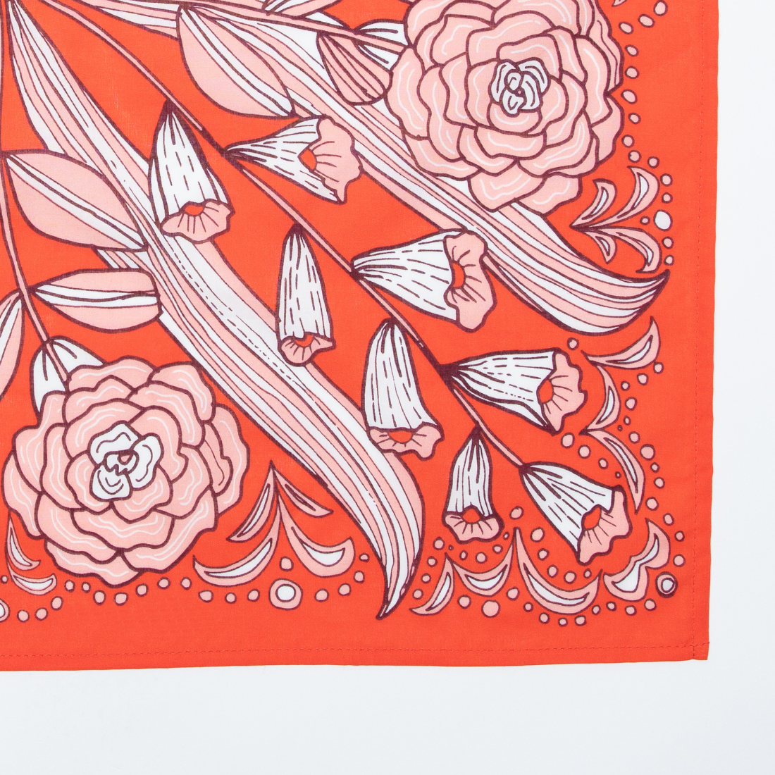 The No. 105 Greta Bandana by Handker Bandanas is a red premium cotton accessory with bold floral motifs—large roses, tulip-like flowers, green leaves, and decorative white dots—symmetrically arranged and hand screen-printed for vibrant detail.