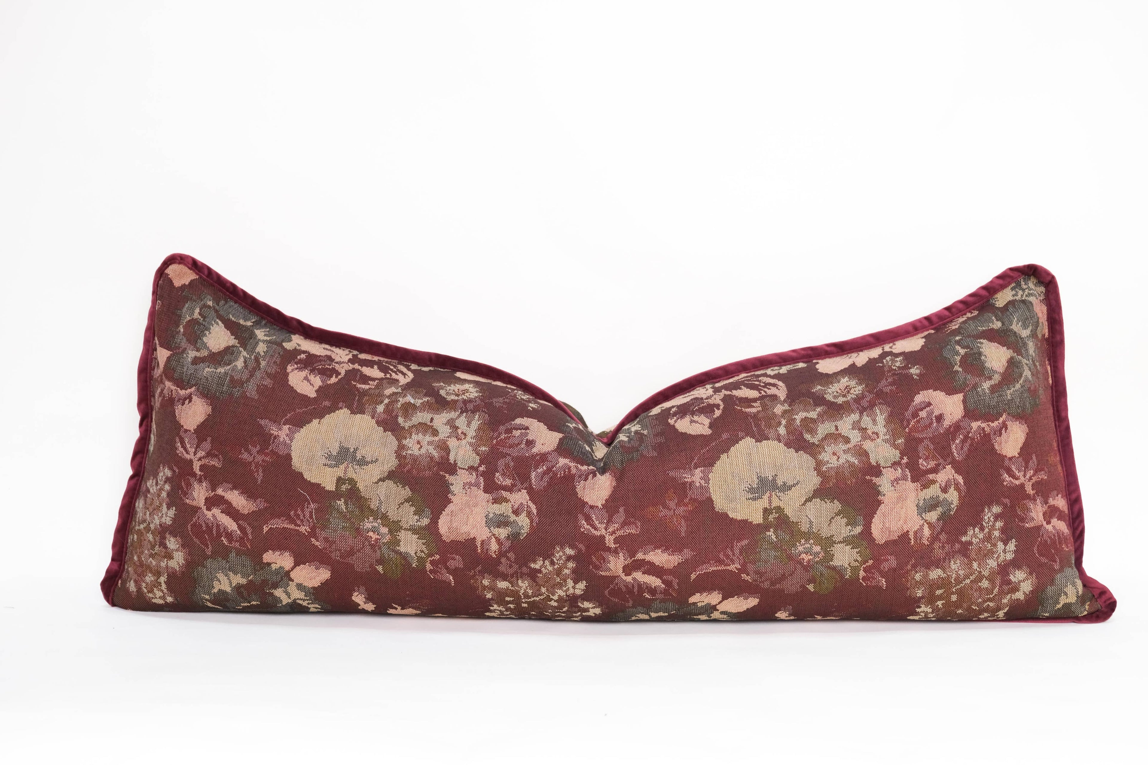 The Tapestry Long Lumbar pillow by Twenty Third by Deanne features a decorative maroon jacquard design with a floral pattern in muted green, beige, and pink on a plain white background.