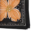 The No. 046 Amy Bandana by Handker Bandanas is a folded cotton accessory featuring a bold orange dogwood flower with yellow accents on a black background, bordered by white dots and lines.