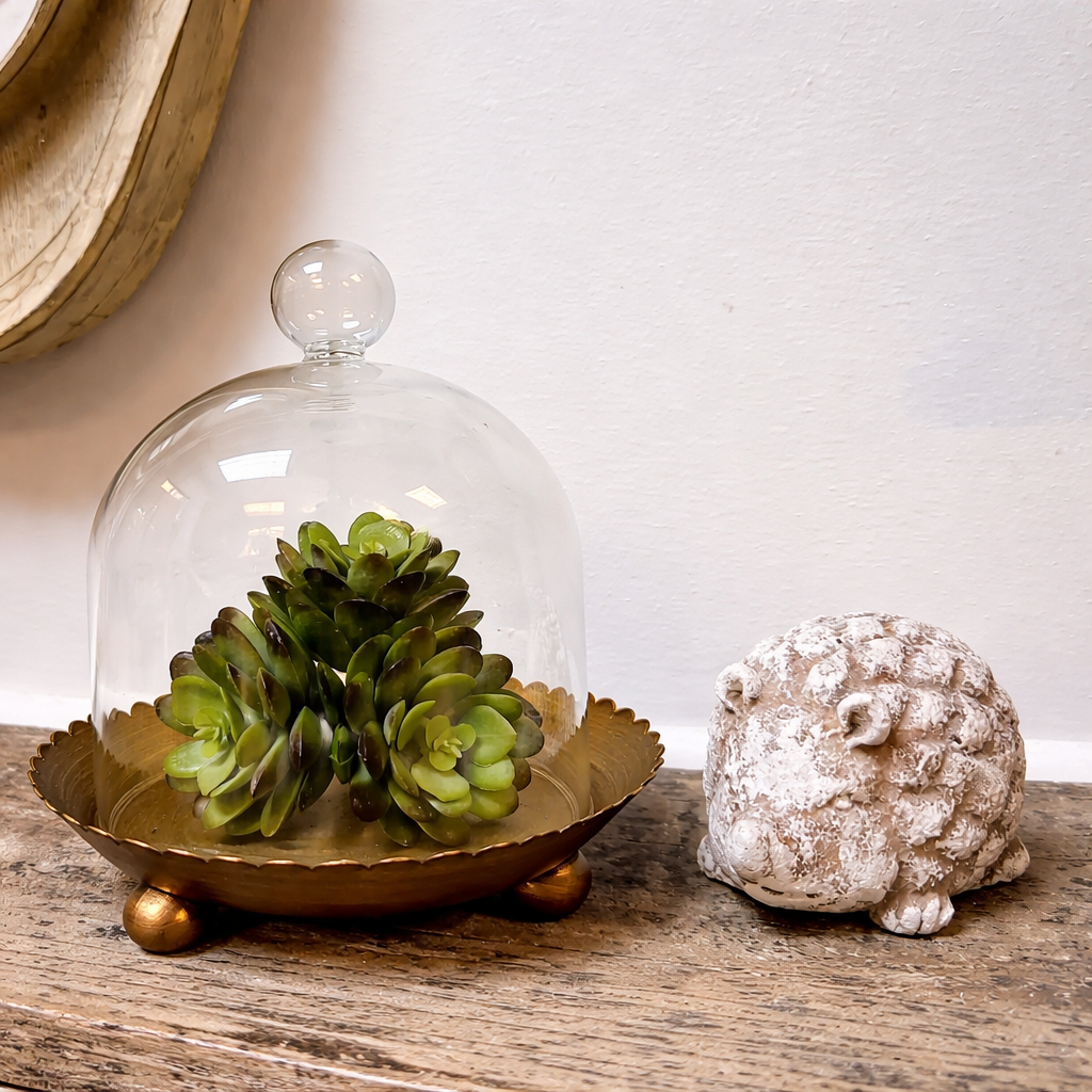 The Vagabond Vintage Cloche Candle Holder with Metal Plate: Gold pairs beautifully with a small succulent and a white hedgehog figurine for charming home decor on any wooden surface.