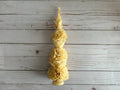 Ivory Large Floral Oaxaca Marigold Day of the Dead Candle: a tall, tapered ivory beeswax candle sculpted with stacked marigold flowers in the style of traditional Oaxaca candles.