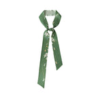 The Lily Silk Twilly Scarf: Green by Lost Pattern NYC features a chic floral print—wear as a stylish hair scarf or gift-ready accessory.
