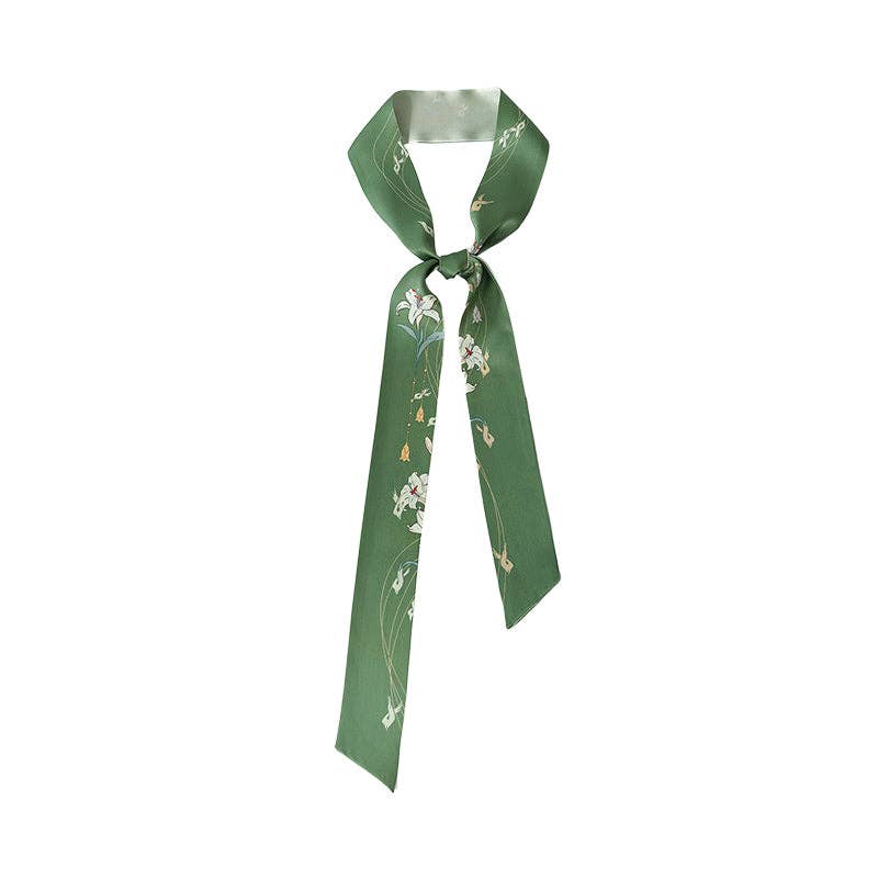 The Lily Silk Twilly Scarf: Green by Lost Pattern NYC features a chic floral print—wear as a stylish hair scarf or gift-ready accessory.