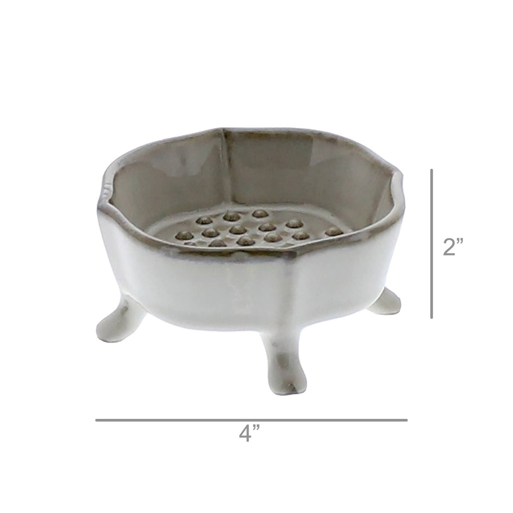 The HomArt Ceramic Rue Footed Soap Dish - Fancy White features three short legs, a scalloped edge, and a raised platform with holes. Measuring 4" wide by 2" tall, it's a charming bathroom accessory for any space.