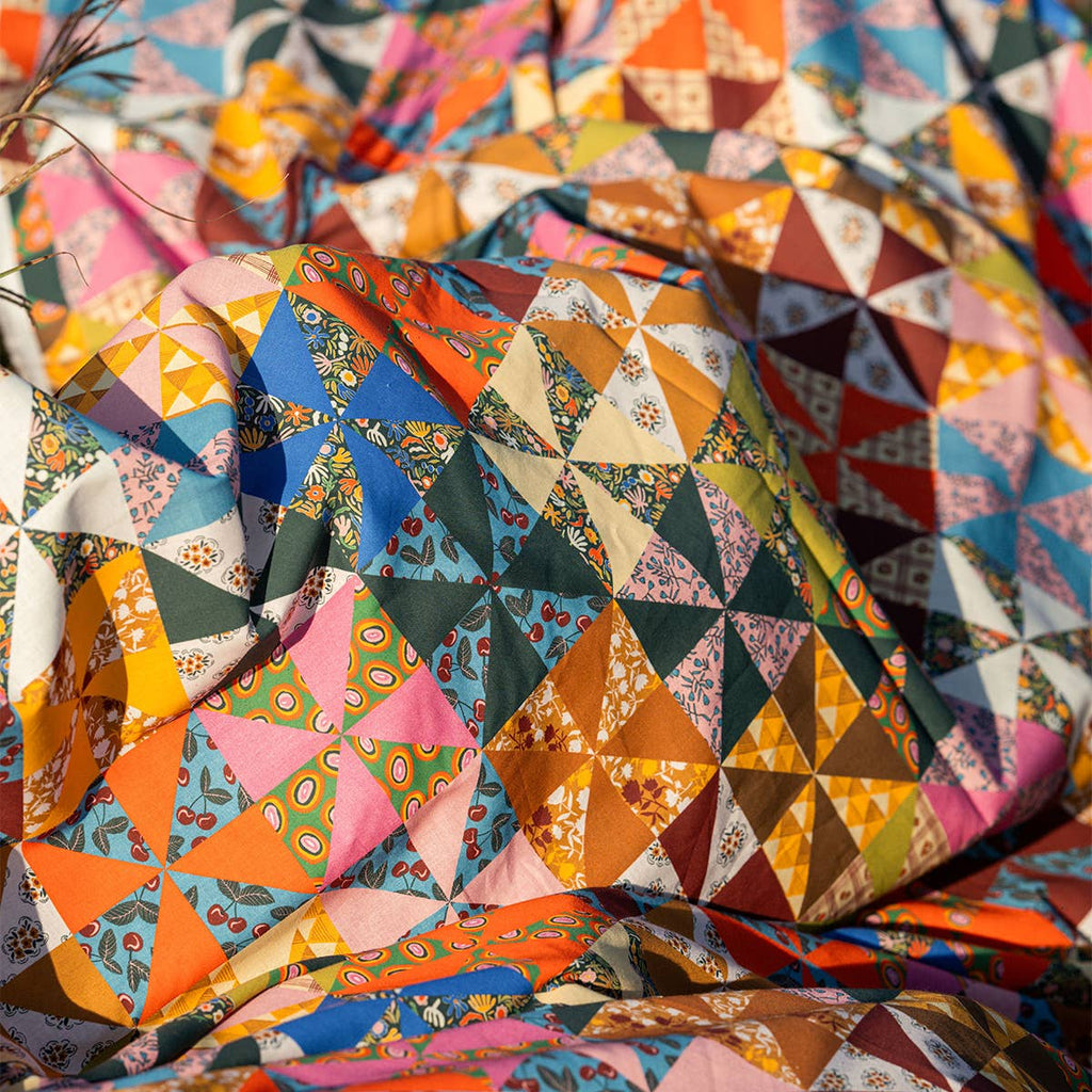 The Calico Quilted Tote by Handker Bandanas features small, patterned triangles in bright colors, creating a vibrant geometric patchwork reminiscent of bandana cotton.