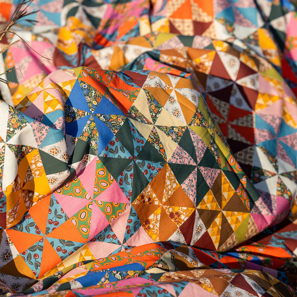The Calico Quilted Tote by Handker Bandanas features small, patterned triangles in bright colors, creating a vibrant geometric patchwork reminiscent of bandana cotton.