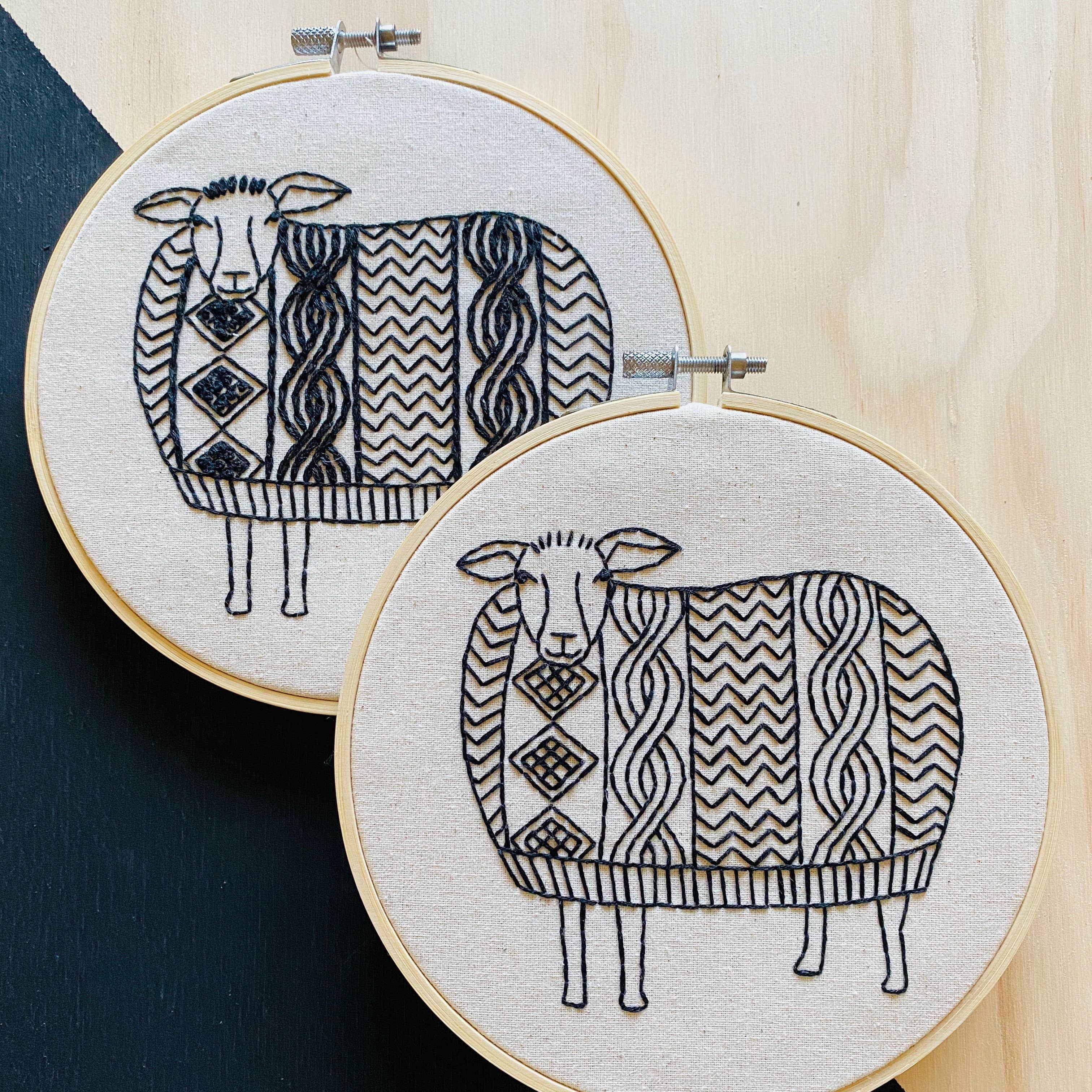 The Sweater Weather Sheep Complete Embroidery Kit by Hook, Line & Tinker features two hoops with sheep stitched in black thread, each with geometric patterned wool—an adorable addition to any embroidery or craft kit.