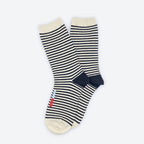 The Cole Black and White Striped Crew Socks by Hooray Sock Co. are unisex crew socks with cream toes, heels, and cuffs, plus small red and blue stripes near the toe on one sock. Perfect for any wardrobe. Set against a plain white background.