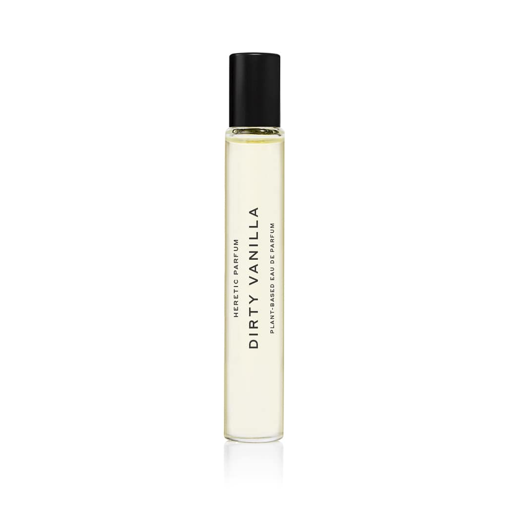 The DIRTY VANILLA ROLLERBALL: 10ML by Heretic Parfum is a clear glass perfume bottle with a black cap, labeled “DIRTY VANILLA,” shown on a white background and featuring warm sandalwood and rich amber notes.