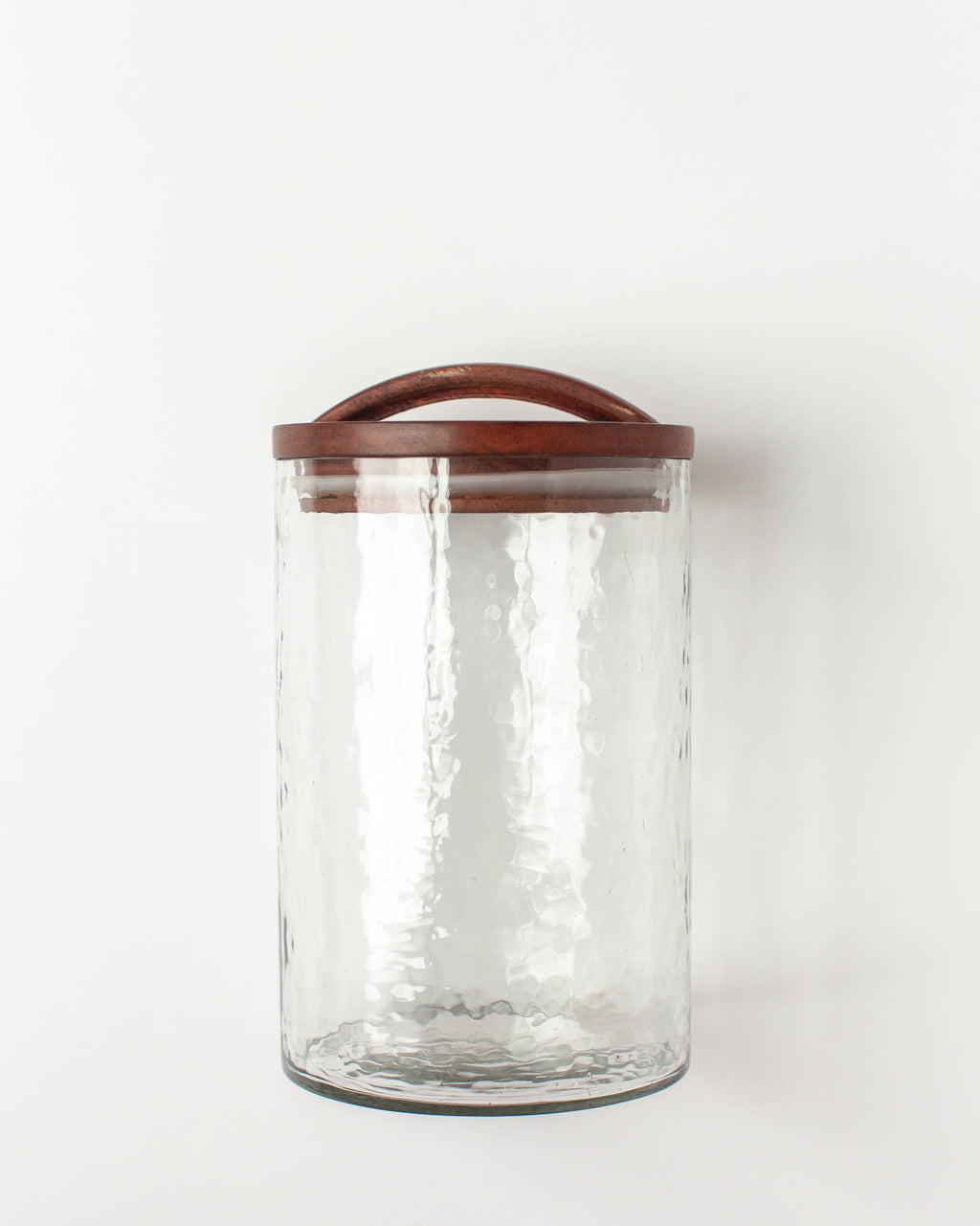 The Handblown Hammered Glass Canisters: Blush / Small by Creative Women features clear textured recycled glass and a hand-carved wooden lid with an airtight seal, shown against a plain white background.