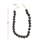 The Black Terracotta Bead + Jute Garland by Foreside Home & Garden features large, round dark beads (1.5" wide) strung on a tan jute cord, forming a 47" loop that adds handmade Indian-inspired decor to any space.