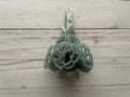 Sage Oaxaca Marigold Day of the Dead Candle, a sage green beeswax taper shaped like a bouquet of marigold flowers.