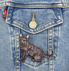 The Wholesale Applique Black Cat Realistic Full Body Embroidered Iron on Patch features yellow eyes and detailed stitching, perfect for customizing blue denim jackets or other outerwear with a unique pet-themed accent.