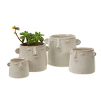 Four Indaba Trading Character Pot S ceramic planters, each shaped like a face with simple features, are grouped together. One mini succulent with yellow flowers sits in a pot, while the other pots remain empty.
