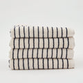 A neatly folded stack of four The Loomia Turkish Cotton Striped Terry Bath Sheets, OEKO-TEX certified in cream with black stripes, displayed against a plain white background.