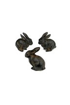 The Vagabond Vintage Small Cast Iron Rabbit figurines, with a rich brown finish, are displayed in a loose triangle on a white background—charming accents to enhance any decor.