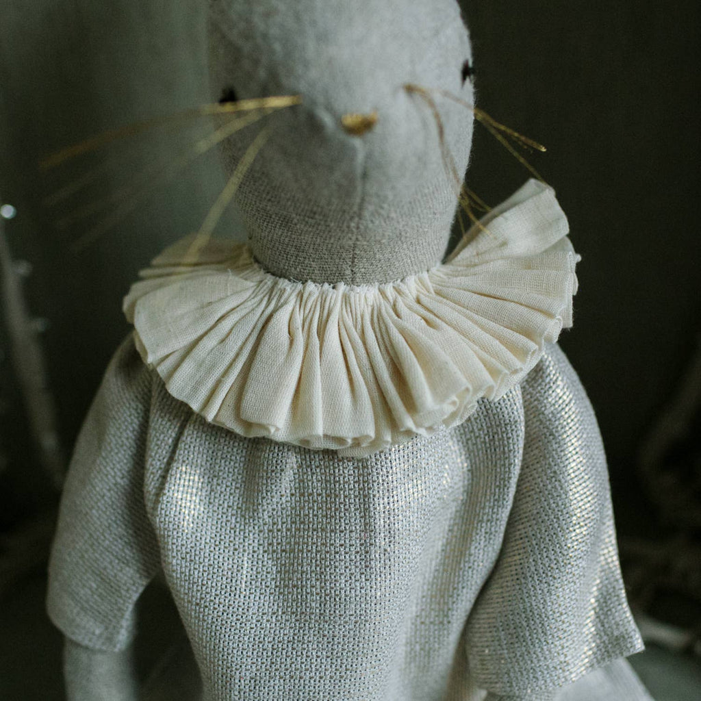 A close-up of the Skippy Cotton Ruffle Bun Ragdoll, a handmade linen art doll with stitched features, cotton filling, thin whiskers, and a cotton dress adorned with a ruffled white collar.