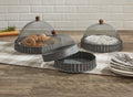 The Park Designs Covington Screen Covers with Bases, set of 3, feature metal mesh and wooden handles on a checkered runner; one is lifted to reveal baked goods while others shield pastries. Plates and forks are stacked nearby. Hand wash for best care.