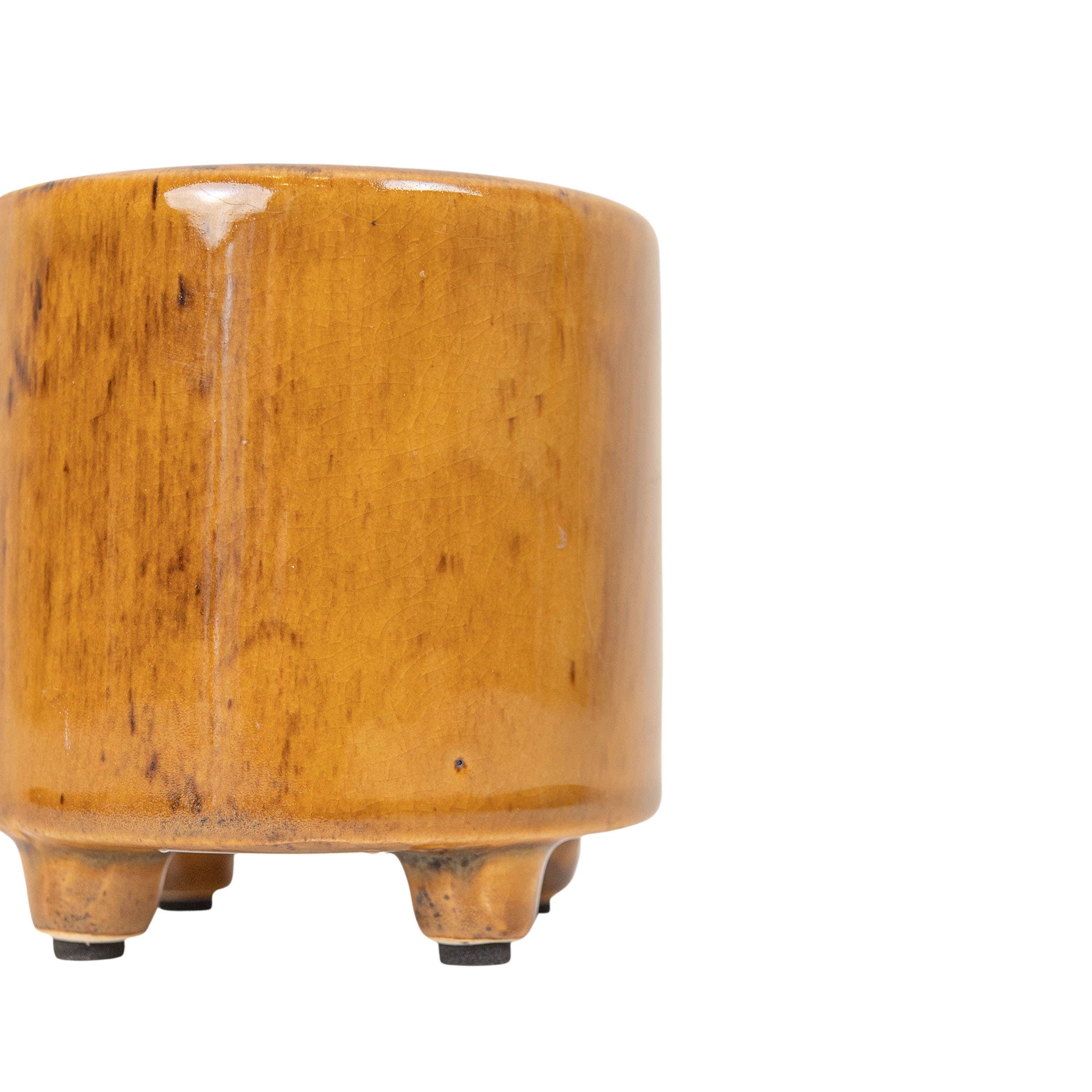 Close-up of the Foreside Home & Garden Glossy Brown Ceramic Planter Pot, resembling a footed vessel, with only its right half visible against a white background.
