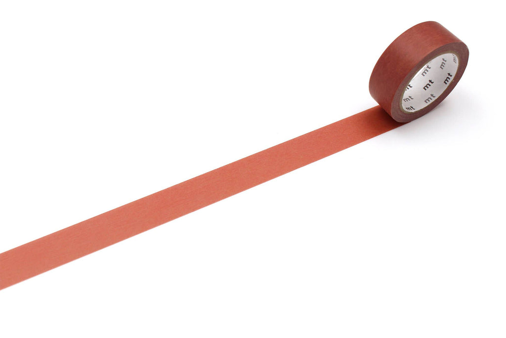 A roll of mt masking tape (Sweet Bella) in reddish brown with a length pulled out across a white surface.