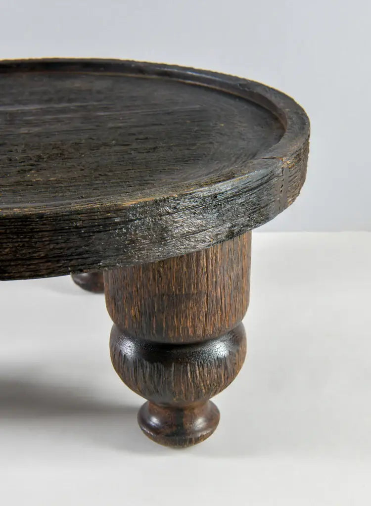 Close-up of the 14in Wide Banjara Reclaimed Look Deep Brown/Black Rugged Wood Stand by Jamali Garden, featuring a thick round tabletop and turned leg—ideal for displaying a mango wood tray against a light background.