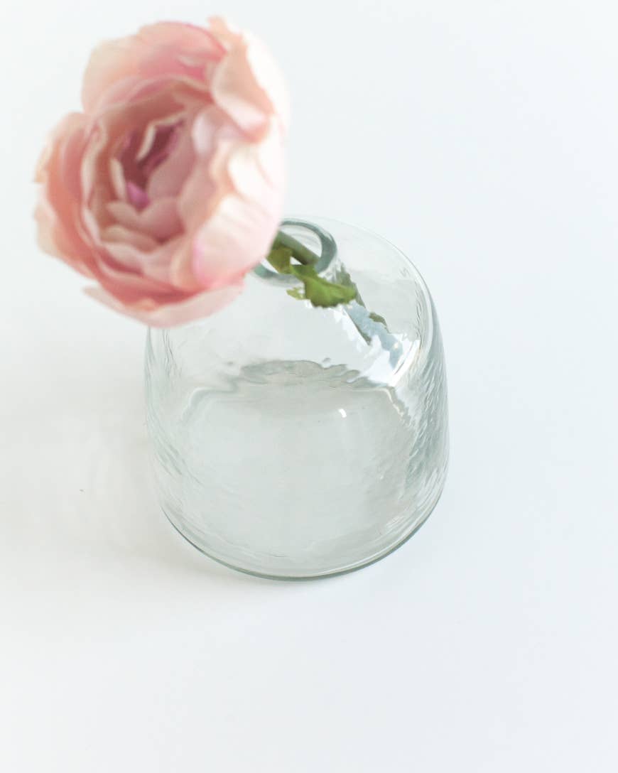 A single pink flower with layered petals in the Bella Handblown Hammered Glass Bud Vase: Blush by Creative Women, set against a white background.