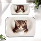 Two small, rectangular Cat Notions Tins from Firefly Notes, handcrafted with a glossy resin coating, each display a realistic illustration of Moody the Cat’s brown and white face. They are shown resting on a white surface with hints of green plants nearby.