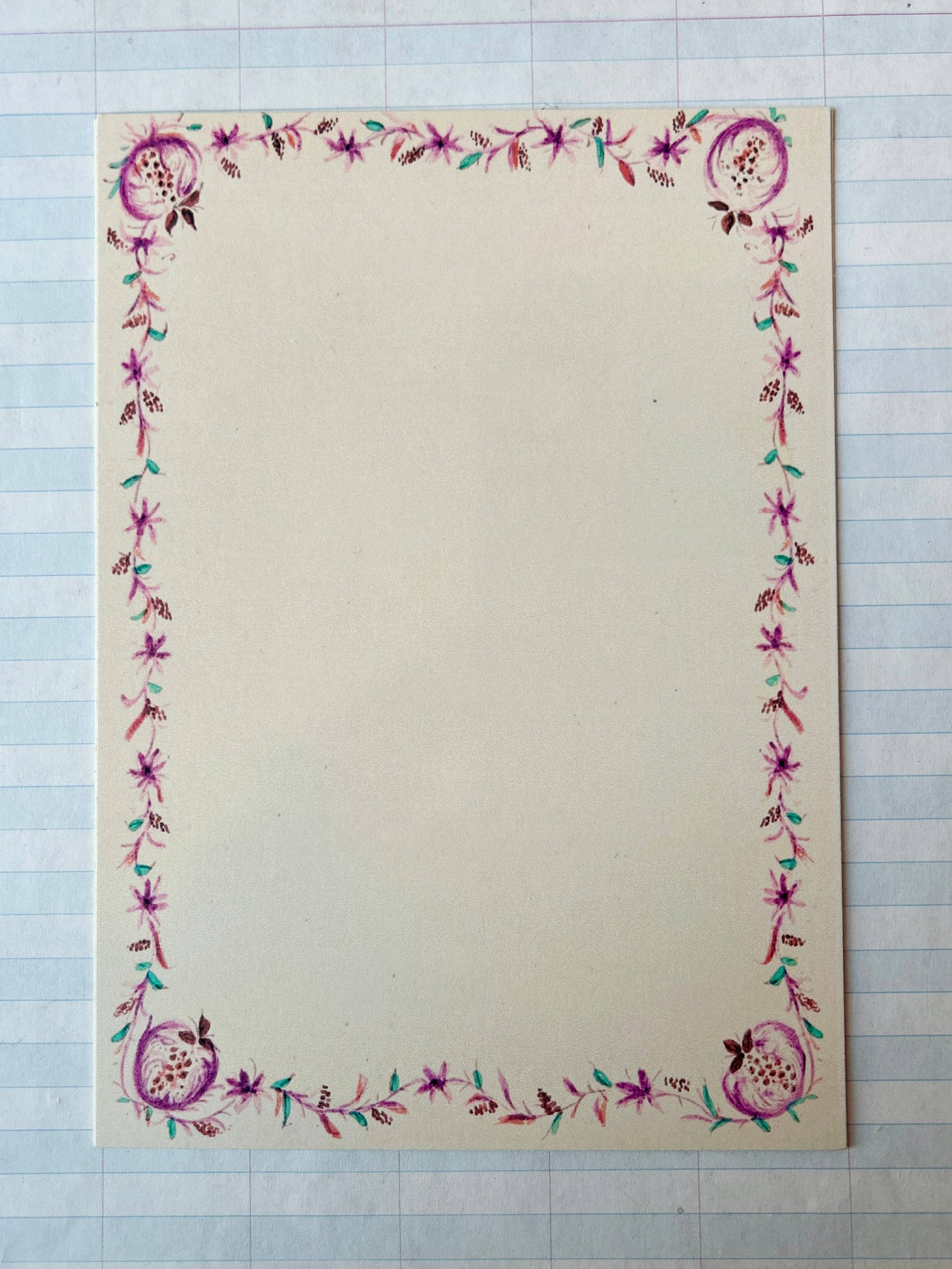 A creamy white card from Parcel's French Menu Stationery Set II: 2 features a pink and purple floral border with green leaves, displayed on graph paper. The elegant set includes 8 printed cards.