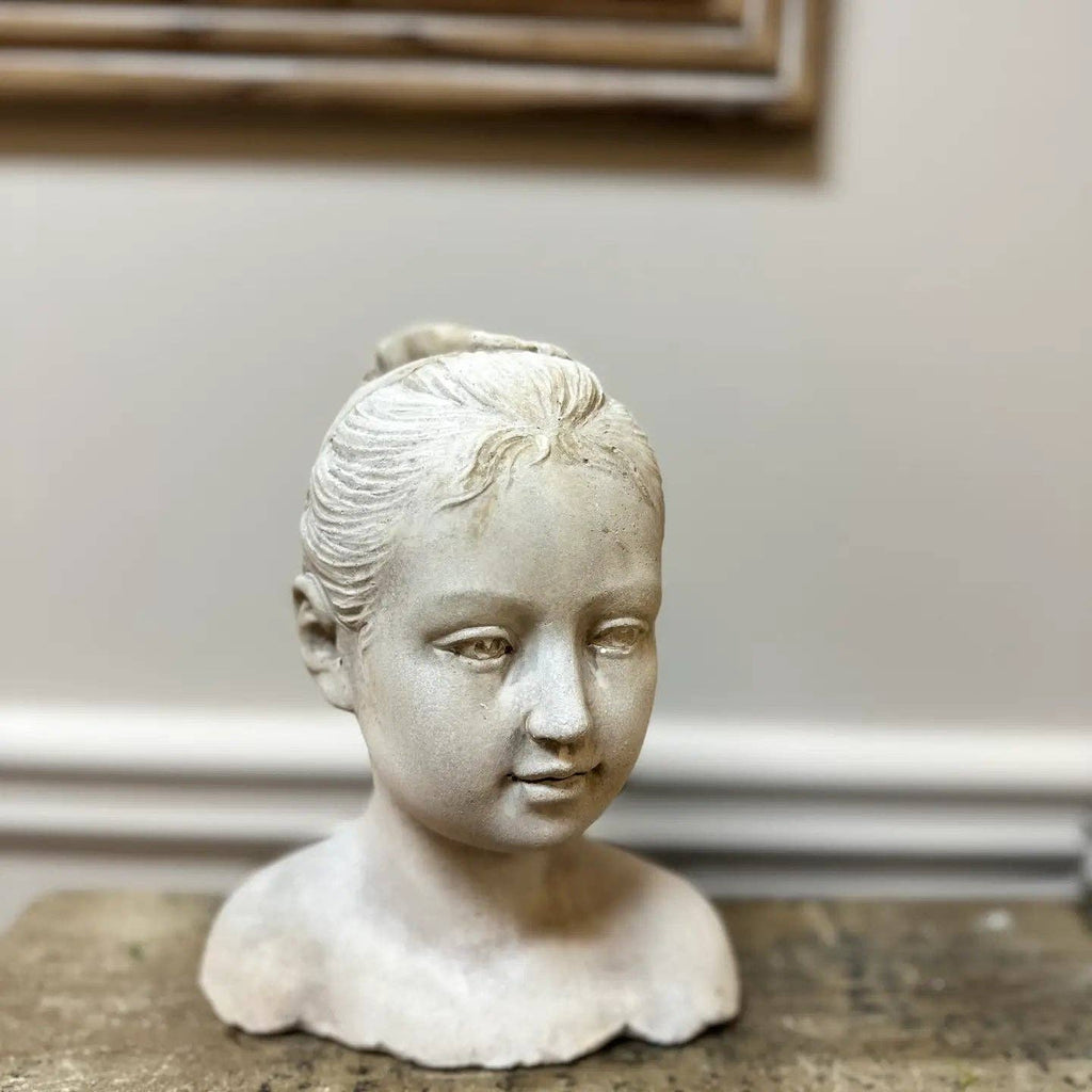 The Cement Girl Statue by Vagabond Vintage is a hand-cast cement bust of a young girl with her hair tied back, ideal as unique garden décor and displayed on wood against a neutral background for a charming accent.