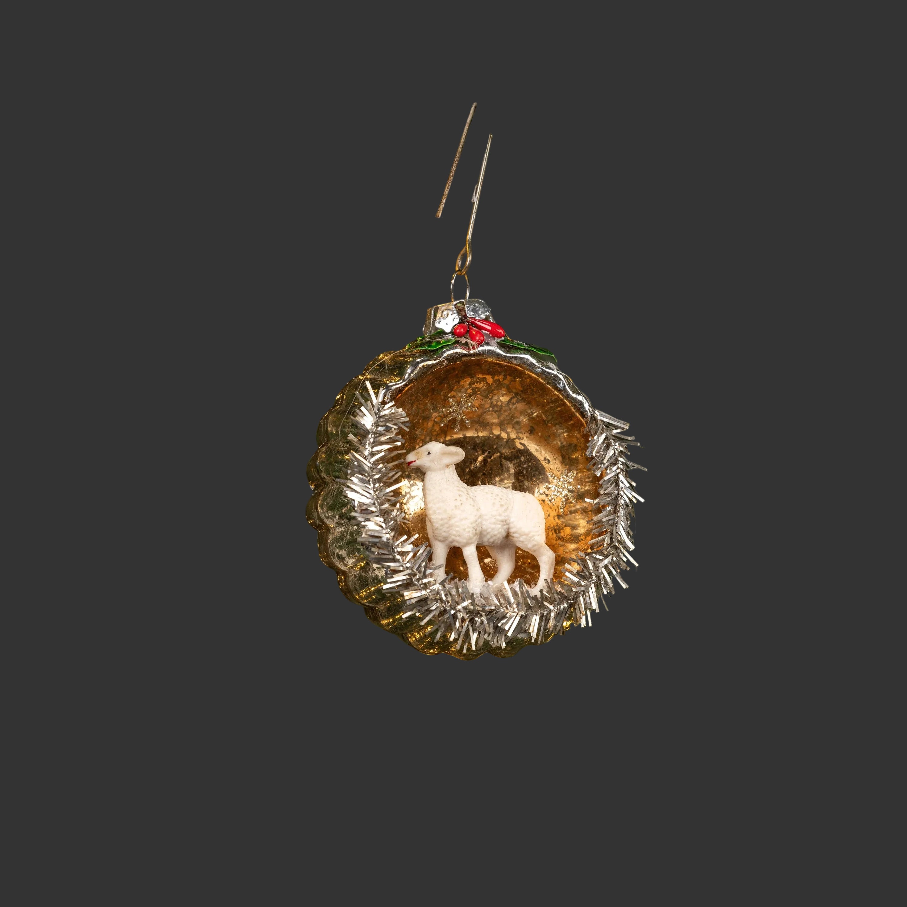 The SHEEP SCENE ORNAMENT by Ragon House is a vintage-style decoration featuring a white sheep in a gold scalloped shell with silver tinsel and red holly, perfect for adding charm to your holiday décor.