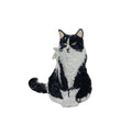 The Tuxedo Cat Iron on Patch by Wholesale Applique features a detailed black and white sitting kitten with green eyes, curled tail, and textured fur, against a white background—perfect for pet lovers.