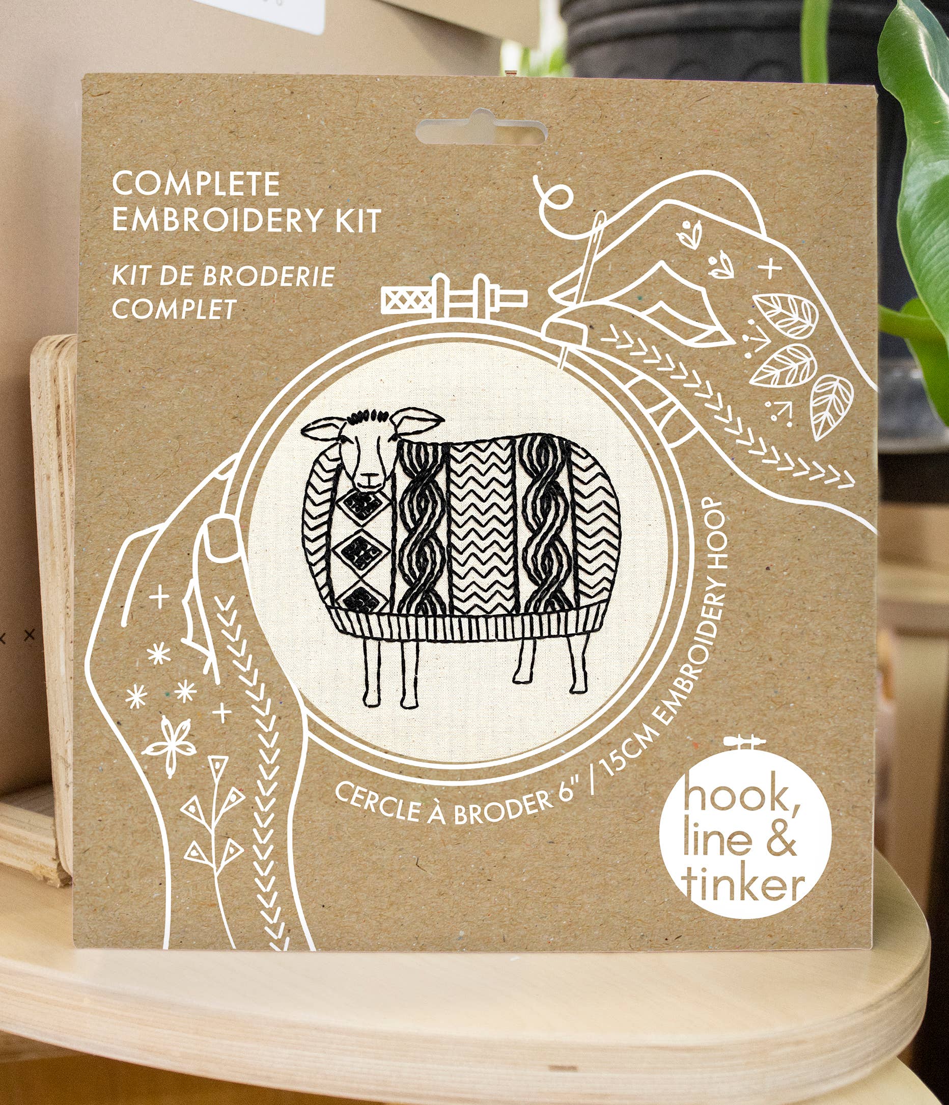 The Sweater Weather Sheep Complete Embroidery Kit by Hook, Line & Tinker Embroidery Kits comes in a cardboard package with a black and white sheep illustration and includes a 6-inch embroidery hoop.